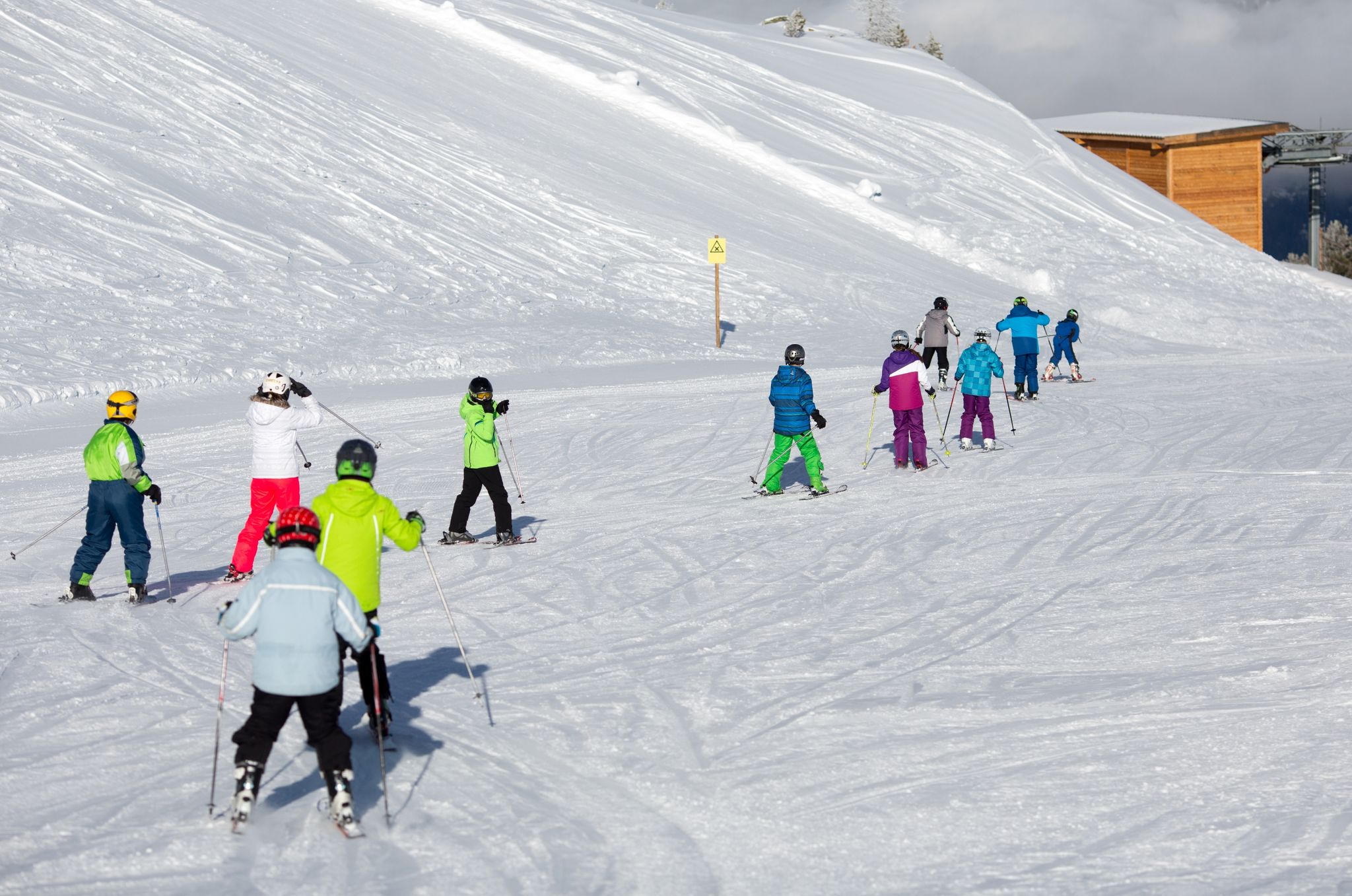 Bekanntes Bild aus den Skigebieten: Skischüler fahren in Reih und Glied die Piste ab.