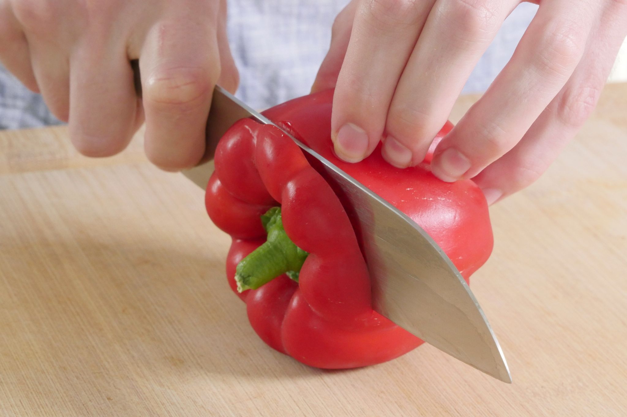 1. Schritt: Wasche die Paprika zuerst und lege sie dann seitlich auf dein Schneidebrett. Schneide dann den oberen Teil kurz vor dem Strunk ab.