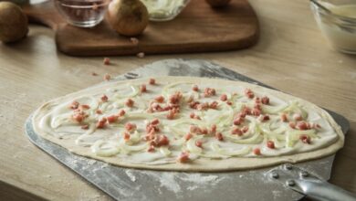 Der typische Elsässer Flammkuchen wird mit Schmand, Speckwürfel und Zwiebeln belegt. Ein Geheimtipp ist es, bereits in den Teig etwas weißen Pfeffer zu geben.