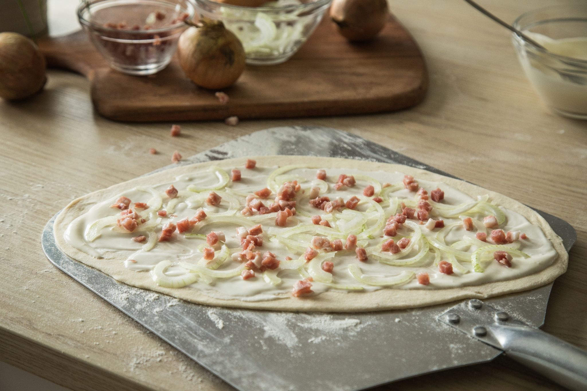 Der typische Elsässer Flammkuchen wird mit Schmand, Speckwürfel und Zwiebeln belegt. Ein Geheimtipp ist es, bereits in den Teig etwas weißen Pfeffer zu geben.