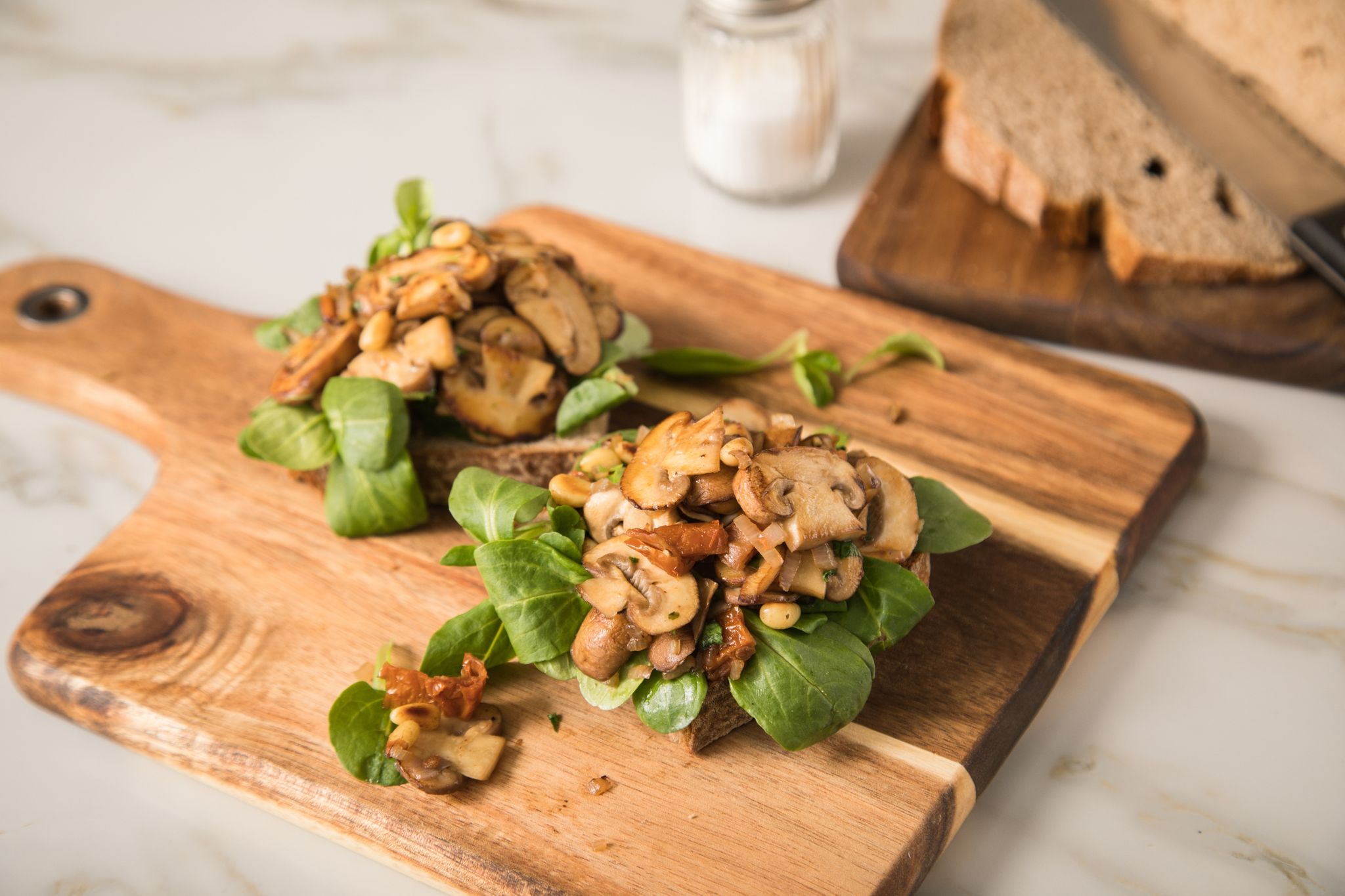 Pilze werden als natürlicher Fleischersatz immer populärer. Statt einer Wurststulle, kann man die Brotscheibe auch mit Champignons, getrockneten Tomaten und Feldsalat belegen.