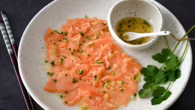Wenn man das Lachs-Carpaccio mit dem asiatischen Dressing beträufelt, wird die Farbe des Fischs etwas heller.