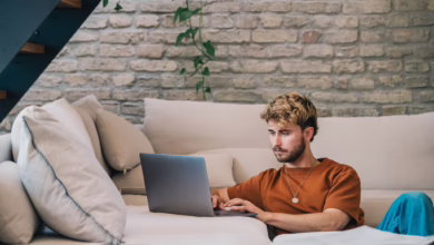 Ein Mann Sitzt Neben Einer Couch Und Arbeitet Am Laptop