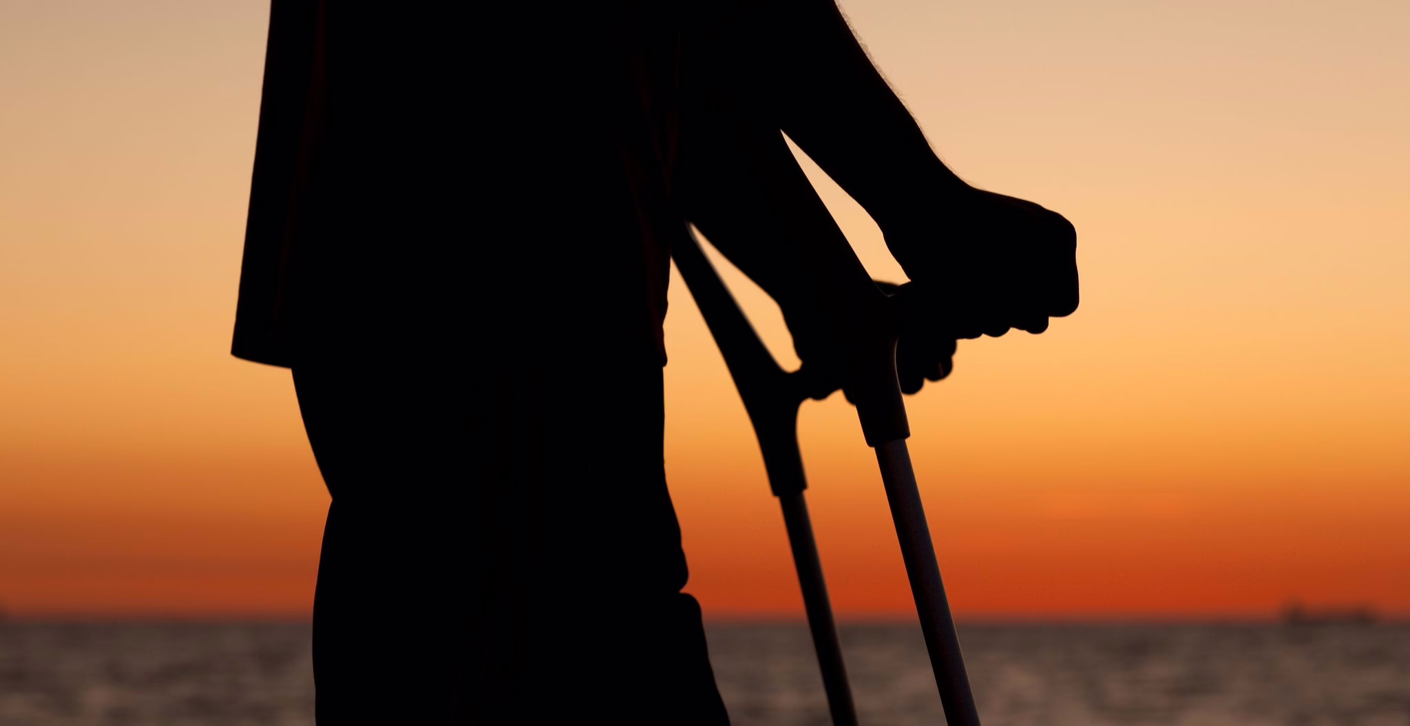 Ein Mann Mit Krücken Bei Sonnenuntergang