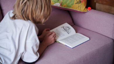 Kind Liest, Während Es Auf Der Couch Liegt