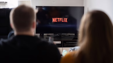 Paar Sitzt Vor Fernseher, Auf Dem Das Netflix Logo Zu Sehen Ist