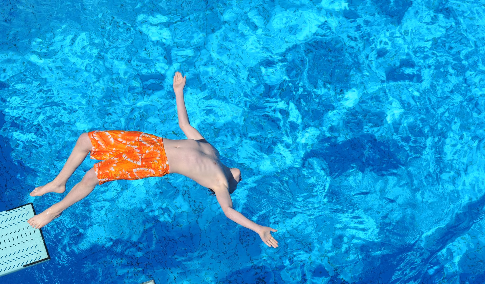 Junge Springt Vom Strungbrett In Das Becken Eines Freibads