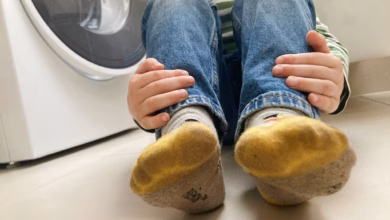 Kind Mit Schmutzigen Socken Sitzt Neben Einer Waschmaschine