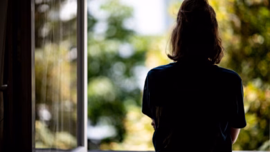 Eine junge frau steht in ihrer wohnung an einem fenster