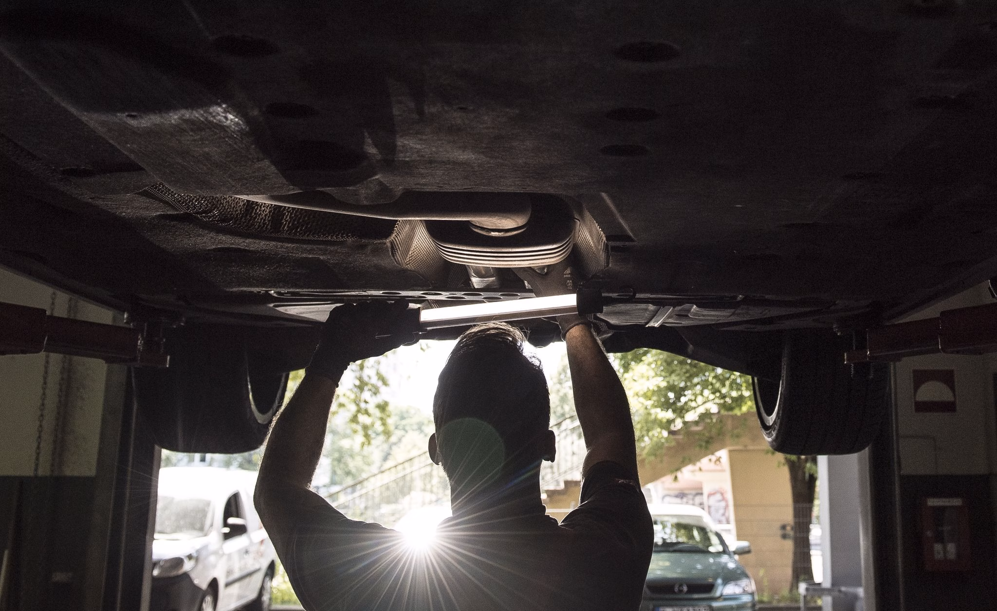Ein kfz mechaniker schaut sich ein auto von unten an