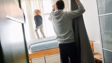 Mann bezieht ein bett während ein kind auf dem bett hüpft