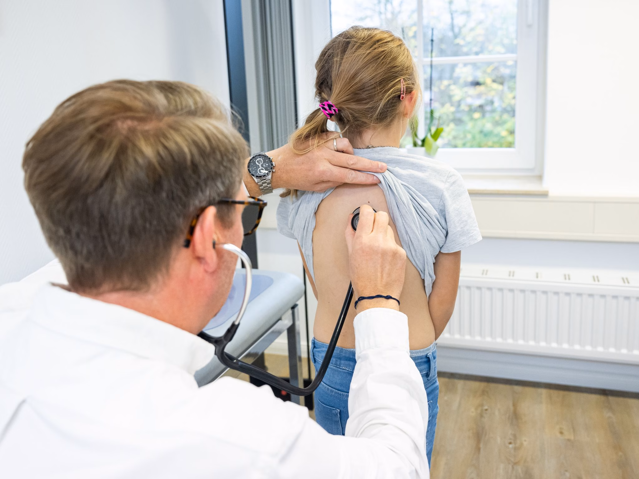 Arzt horcht mit einem stethoskop die atemwege eines kindes ab