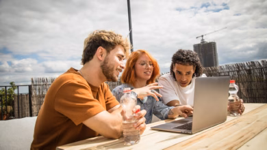 Junge leute sitzen auf einer dachterrasse vor einem laptop