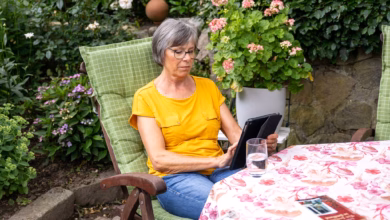 Eine seniorin sitzt mit einem tablet im garten