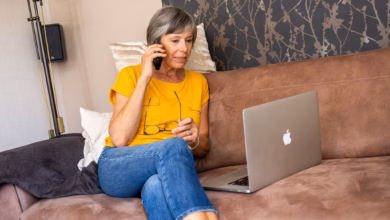 Eine ältere frau telefoniert und schaut auf ihren laptop