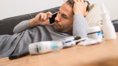 Mann liegt krank auf einem sofa und telefoniert