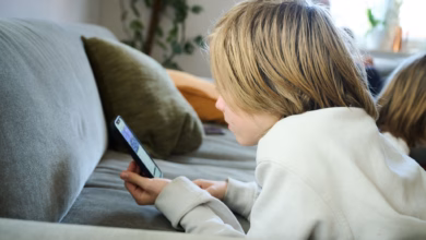 Ein junge liegt auf einem sofa und guckt auf sein smartphone