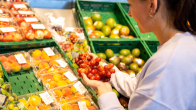 Eine frau begutachtet trauben in einem supermarkt