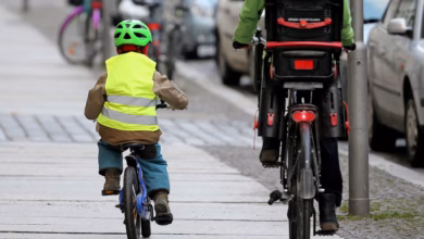 Ein kind fährt mit dem rad auf dem fußweg neben einem elterteil