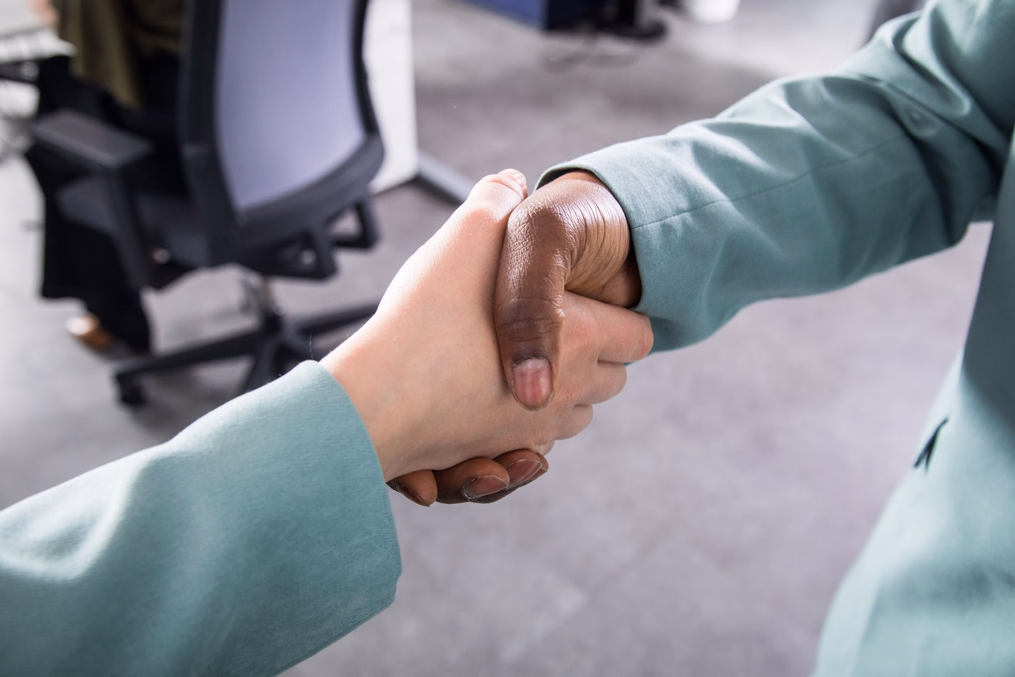 Zwei personen reichen sich in einem büro die hand