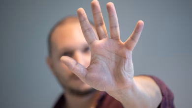 Ein mann hebt schützend die hand vor sein gesicht