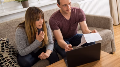 Ein paar ließt einen brief und sitzt am laptop