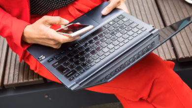 Eine frau sitzt mit smartphone und laptop auf einer bank