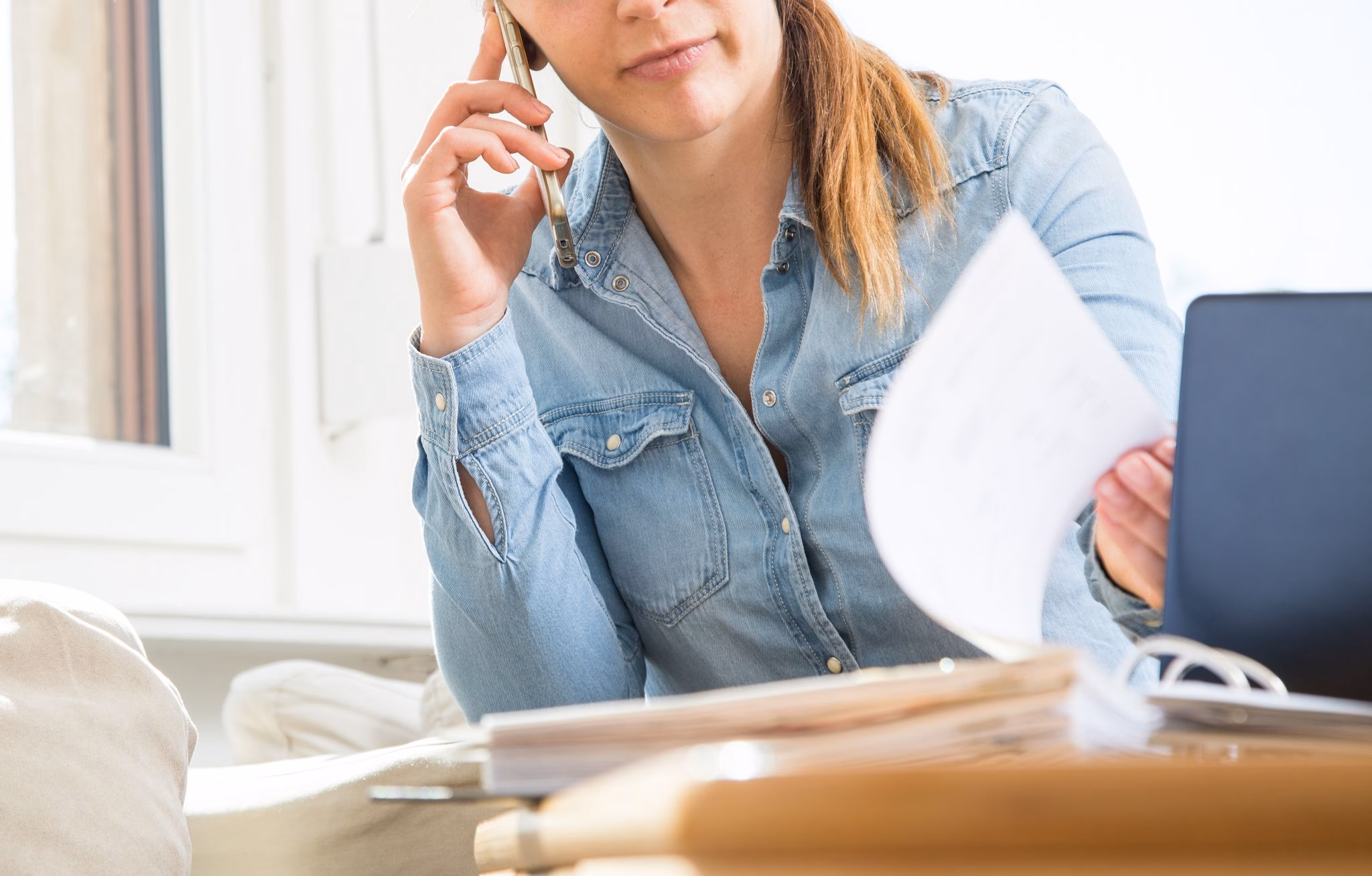 Eine frau telefoniert und liest unterlagen durch