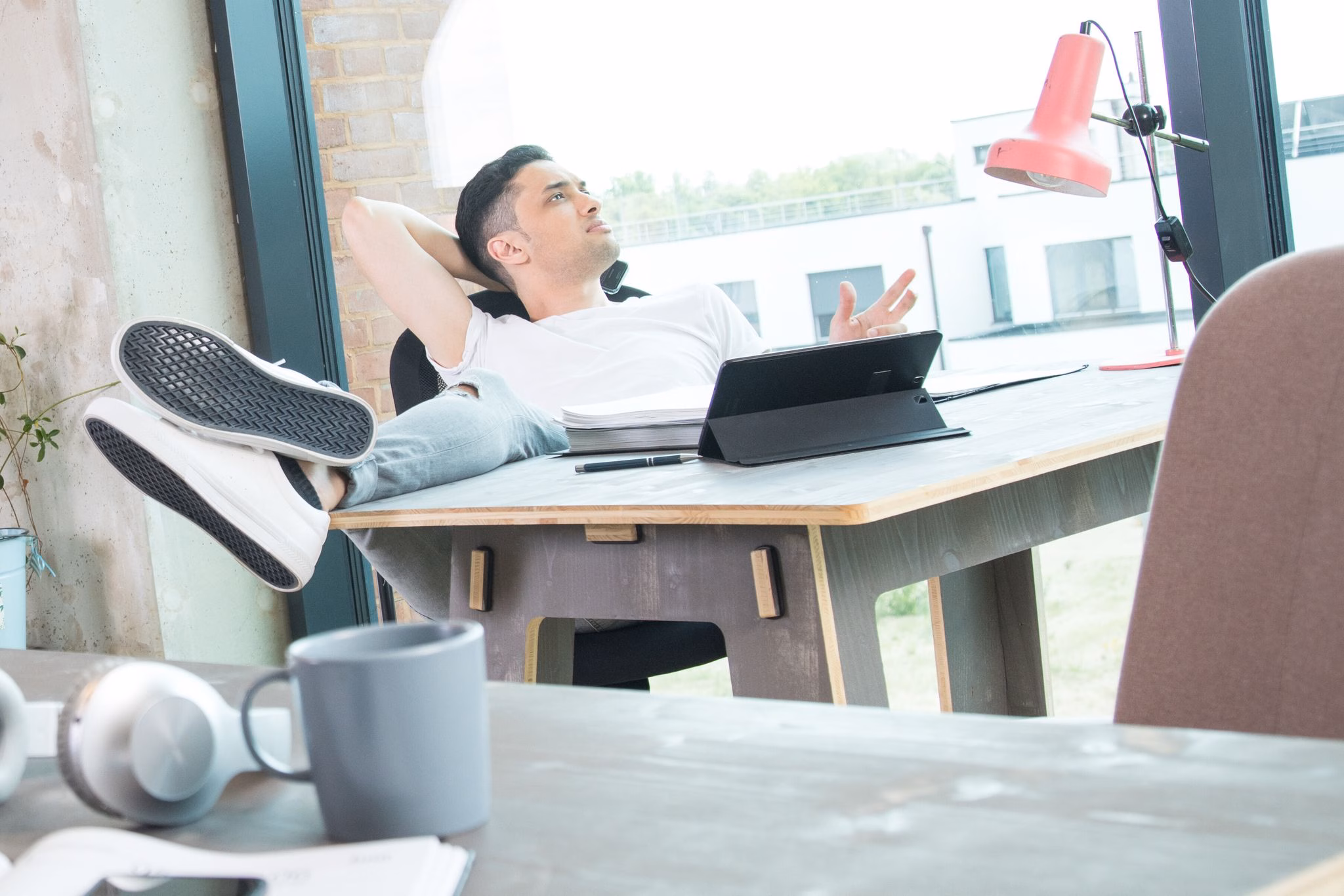 Mann schaut an seinem schreibtisch aus dem fenster