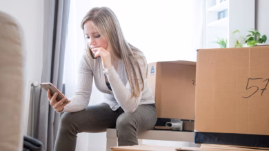 Eine frau sieht zwischen umzugskartons auf ein handy