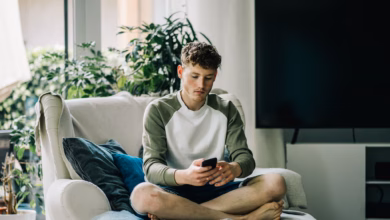 Ein junger mann sitzt mit smartphone auf einem sessel
