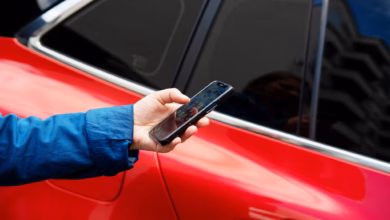 Eine person steht mit einem smartphone neben einem auto