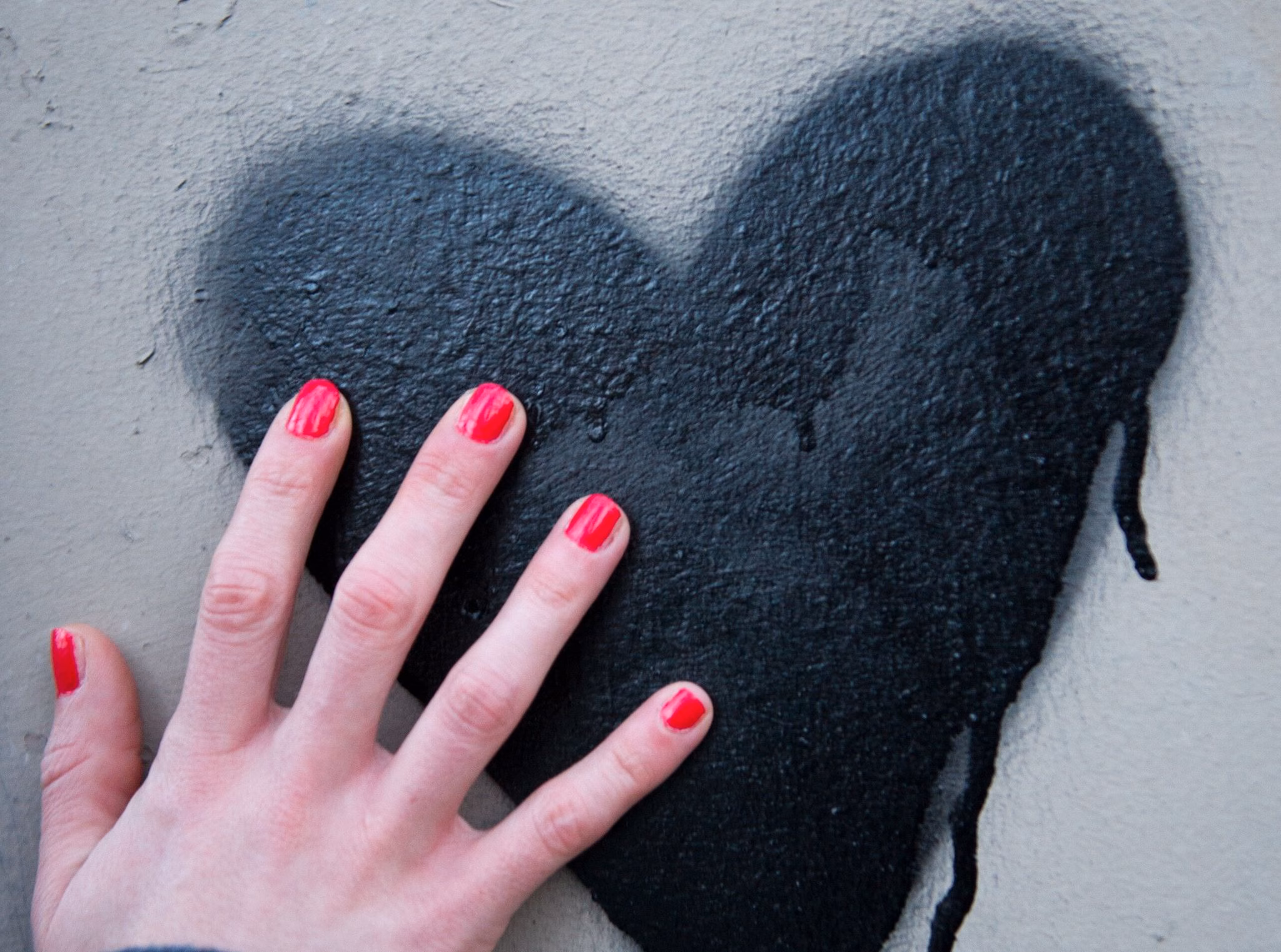 Frauenhand berührt ein auf die wand gesprühtes herz