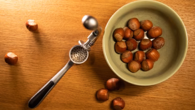 Haselnüsse liegen neben einer knoblauchpresse