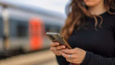 Eine junge frau steht mit ihrem mobiltelefon auf einem bahnsteig