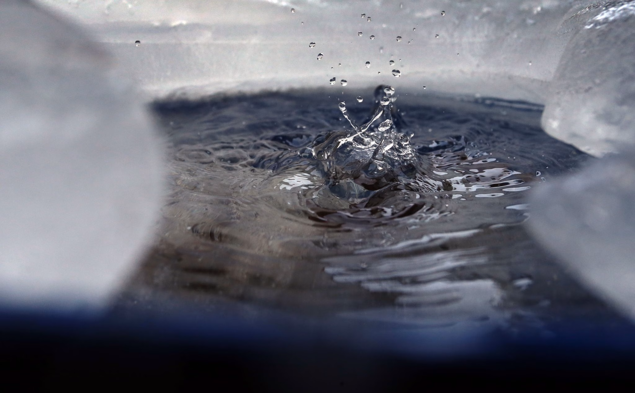 Wasser tropft in eine von eis umgebene regentonne