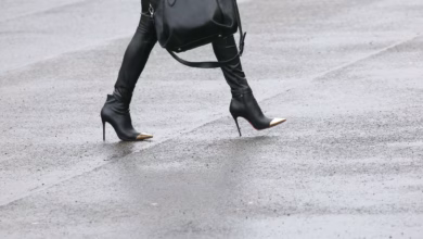 Frau mit high heels geht über eine regennasse straße