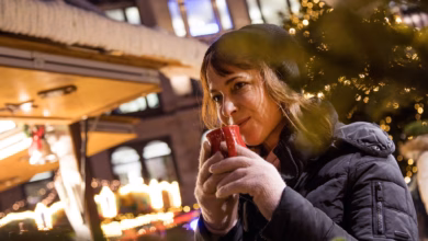 Frau trinkt auf dem weihnachstmarkt ein heissgetränk