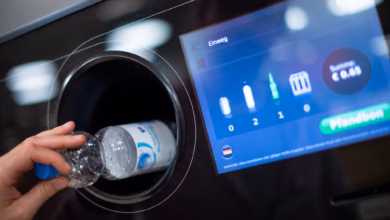 Ein mann steckt eine pfandflasche in einen leergutautomaten