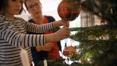 Mutter und tochter schmücken gemeinsam den weihnachtsbaum